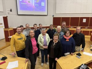 Keskustan valtuutetut ja varavaltuutetut ryhmäkuvassa. Kuvassa on naisia ja miehiä Viitasaaren kaupunginvaltuuston salissa. 