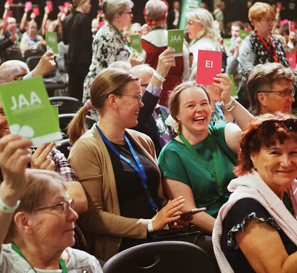 Jyväskylän puoluekokouksen osallistujia osallistumassa äänestykseen vihreiden ja punaisten äänestyslippujen kera.